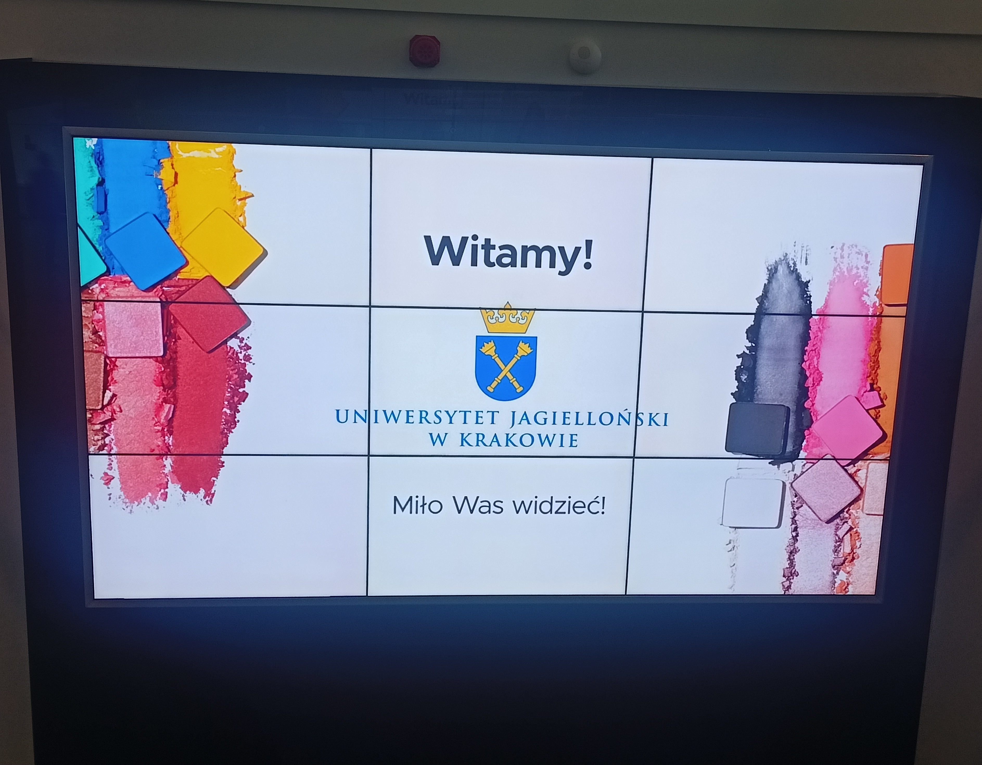 Zdjęcie przedstawia slajd prezentacji na którym widać kolorowe cienie oraz napis Witamy! Uniwersytet Jagielloński w Krakowie. Miło Was widzieć!